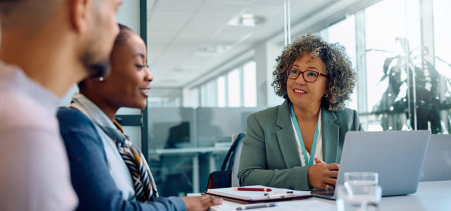 Three people sitting at a table talking.